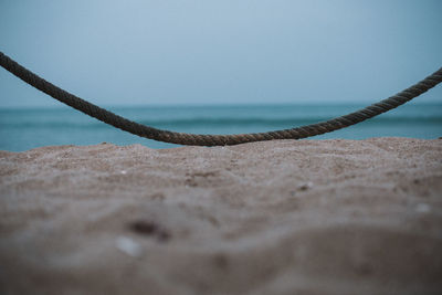 Close-up of rope on beach against clear sky