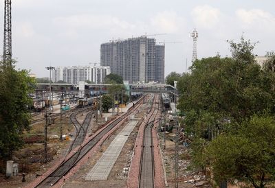 Railroad tracks amidst buildings in city against sky