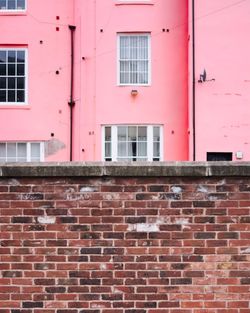 Brick wall against pink building in city