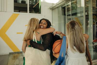 Smiling teenage girl hugging female friend in mall