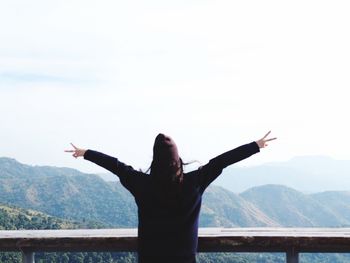 Rear view of man with arms outstretched against mountain range