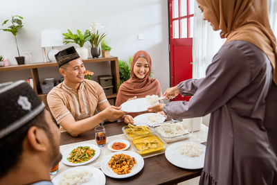 Smiling woman serving food to guests at home