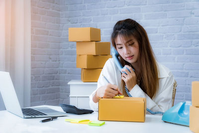 Portrait of woman using phone while sitting on table