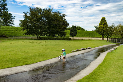 Man riding bicycle on grassy field against sky