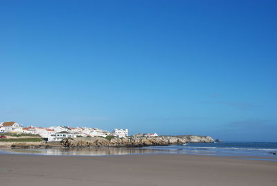 Calm beach with built structures against blue sky