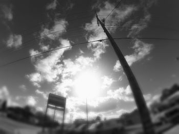 Low angle view of power lines against cloudy sky