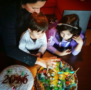 Mother preparing cake with children at home