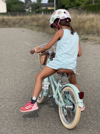 Little girl with helmet  riding mint color bicycle on road