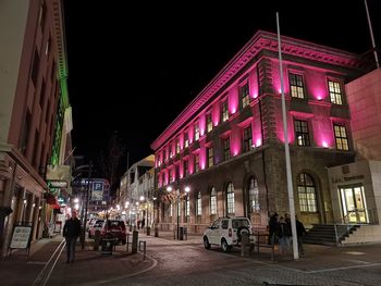 People on street amidst buildings in city at night