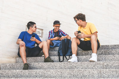 Friends sitting on steps sharing smart phone