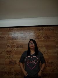 Portrait of beautiful woman standing against wall at home