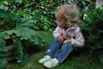 High angle view of girl picking while sitting on field