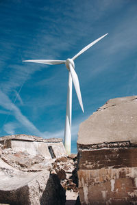 Wind turbine by sea against blue sky