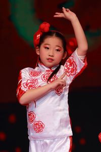 Cute girl in traditional clothing against black background