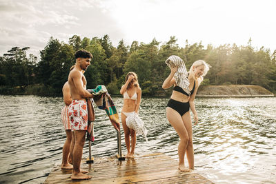 Male and female friends enjoying by lake during vacation