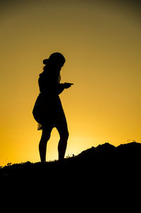 Silhouette man standing against orange sky