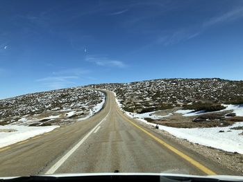 Road leading towards snowcapped mountain against sky