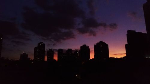 Silhouette buildings against sky at sunset