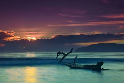 Silhouette boat in sea against sky during sunset