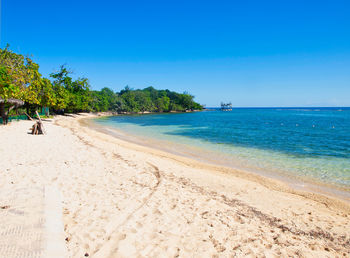 Scenic view of beach against clear blue sky