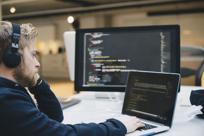 Side view of businessman programming on laptop at creative office