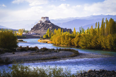 Scenic view of river by mountains against sky