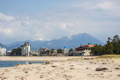 Houses on beach by buildings against sky