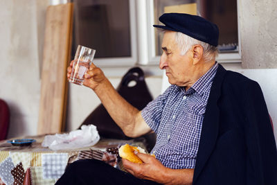 Senior man having food and drink while sitting on seat