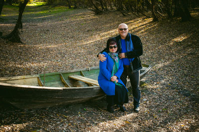 Portrait of smiling mature couple by boat at forest during autumn