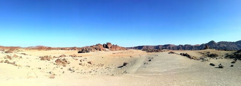 Panoramic view of desert against clear blue sky