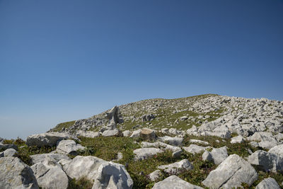 Low angle view of rocks against clear blue sky