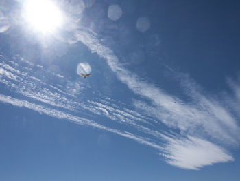 Low angle view of sun shining through clouds