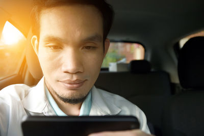 Close-up of man using phone while sitting in car