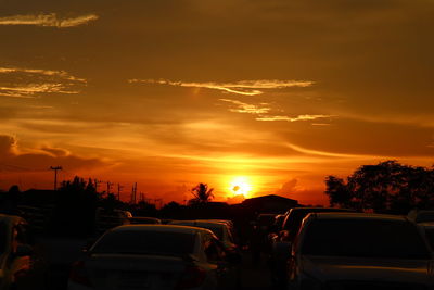 Cars on street against sky at sunset