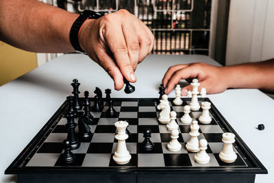 Cropped hands of men playing chess at table