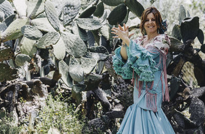 Portrait of smiling woman clapping against plants