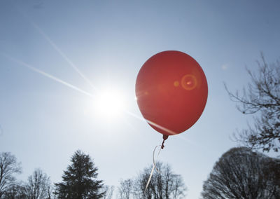 Red balloon and blue sky background with sun, symbol for joy and happiness