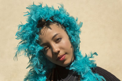 Close-up portrait of woman wearing turquoise feather boa on sunny day