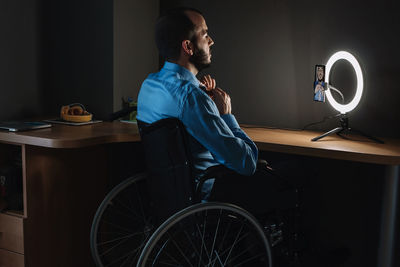 Side view of young man sitting on table