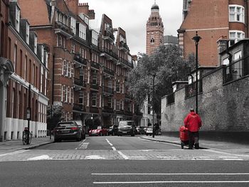 Rear view of man on street amidst buildings in city