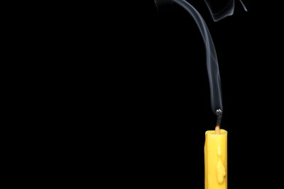 Close-up of candle and smoke against black background