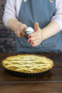 Women preparing delicious apple tart or pie large on wood table background.sprinkle powdered sugar