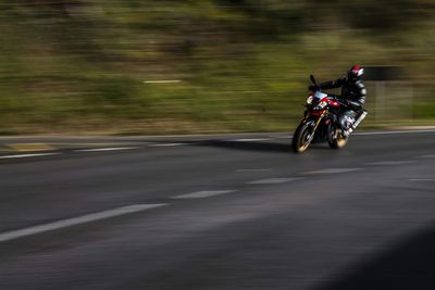 Blurred motion of man riding motorcycle on road