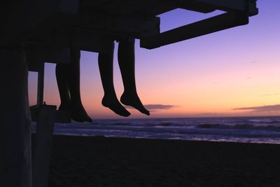 Low section of silhouette people on beach during sunset