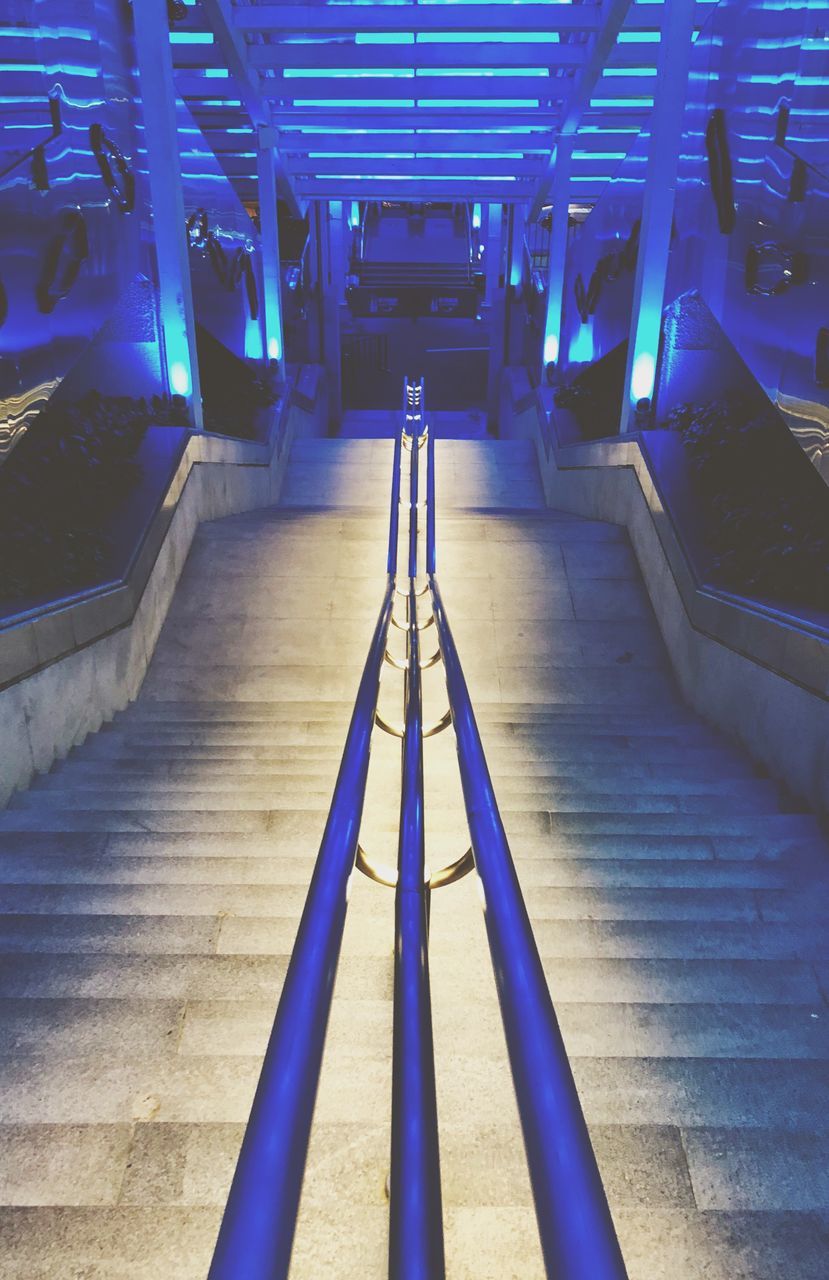 architecture, the way forward, illuminated, staircase, railing, direction, indoors, steps and staircases, built structure, empty, blue, no people, diminishing perspective, lighting equipment, transportation, metal, absence, technology, connection, ceiling