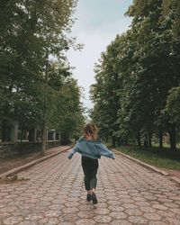 Rear view of woman walking on footpath amidst trees