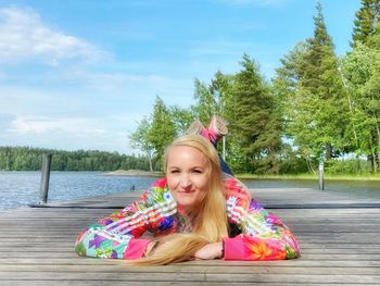 Portrait of smiling woman against pink and trees against sky