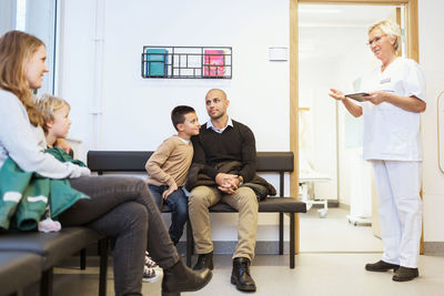 Nurse talking to patients sitting in waiting room at orthopedic clinic