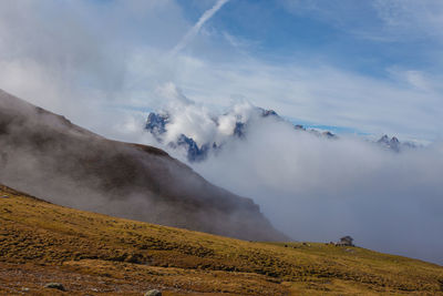 Sunrise on a pasture and on dolomite peaks hidden by clouds, south tyrol, italy