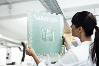 Mature businesswoman analyzing large computer chip in industry